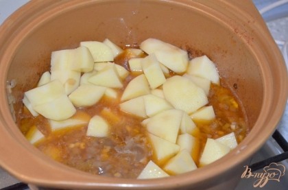 Мясо переложить в кастрюлю с луком, добавить мелко нарезанный чеснок, перемешать. В кастрюлю добавить воды, чтобы немного покрывала мясо и тушить на медленном огне примерно 1,5 часа, пока мясо не станет мягким. Периодически нужно подливать воду. Когда мясо будет готово, добавить в кастрюлю нарезанный кубиками картофель, варить 10-15 мин.