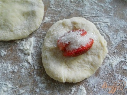 Разделить тесто на части, каждую - раскатать колбаской и порезать на небольшие кусочки. Из кусочков сделать лепешки (не тонкие). В центр лепешки поместить клубнику (порезанную на 2-4 части, если мелкая - целые ягодки), посыпать чуть сахаром.