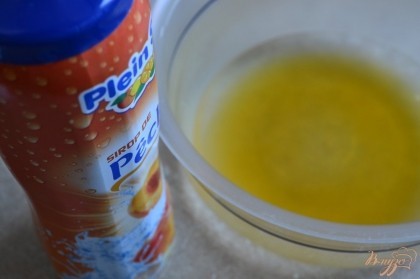 В миску налить теплую воду и сироп (абрикосовый или персиковый)