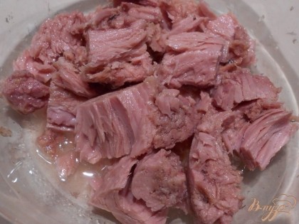 Для салата используем консервированный тунец в собственном соку. Вскрываем банку с тунцом и сливаем жидкость. В салатник выкладываем кусочки тунца.