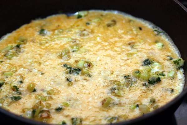 Вылейте яичную смесь в сковороду к овощам и готовьте на маленьком огне под крышкой до загустения.