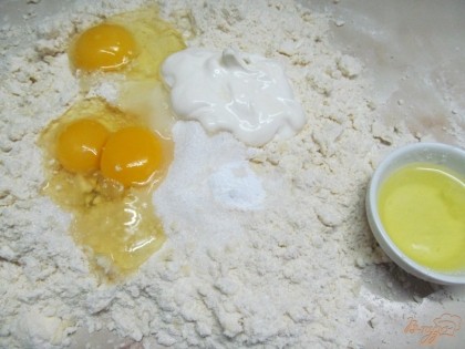 Добавить соду, сахар, сметану и 3 яйца. У четвертого яйца белок отделить от желтка. Желток добавить в тесто, а белок понадобится для смазки пирога.