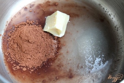 Пока готовятся пряники, сделаем шоколадную глазурь. В кастрюлю наливаем 50 мл. воды, насыпаем сахар и 3 ч. ложки какао. Так как пряники постные можем использовать масла только растительного происхождения. Небольшой кусочек какао-масла добавим в глазурь и ставим кастрюлю на огонь. Варим глазурь до загустения, непрерывно помешивая.