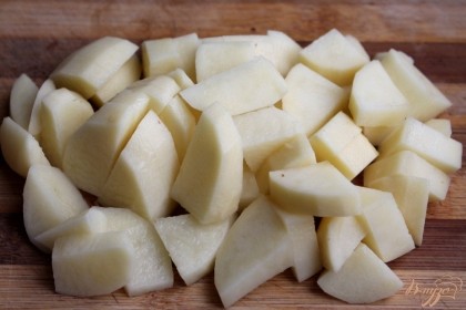 Далее, чистим и нарезаем картофель. Кусочки картофеля высыпаем в кастрюлю к остальным овощам.