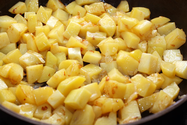 Добавьте очищенную и нарезанную кубиками картошку, перемешайте и готовьте 15 минут, периодически помешивая. Посолите и поперчите.