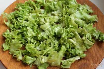 Листья салата промываем в холодной воде, просушиваем, нарезаем и выкладываем на плоскую тарелку.
