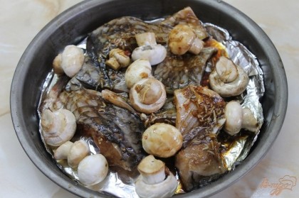В противень на дно положить фольгу, смазать ее растительным маслом. Выложить рыбу и грибы, полить маринадом с рыбы. Накрыть фольгой и отправить в духовку на 20 минут.