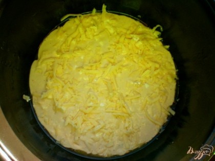 Тесто смешиваем с сыром фета и выливаем его в смазанную маслом чашу для мультиварки. Сверху на тесто посыпать твёрдый сыр.