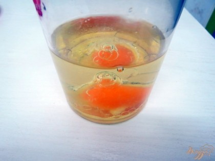 На дно стакана разбиваем яйцо и заливаем его растительным маслом.