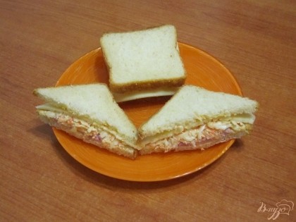 Сверху положить ломтик сыра и накрыть хлебом. Разрезать бутерброд по диагонали.