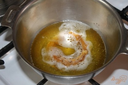 В глубокую металлическую посуду налить растительное масло и обжарить луковые колечка.