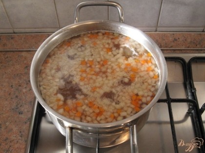 Добавить лук и морковь в бульон. По вкусу посолить, поперчить. Варить в течение 35 минут.