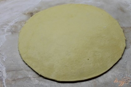 Готовое дрожжевое тесто на пиццу раскатать тонко и обрезать с помощью круглой доски.
