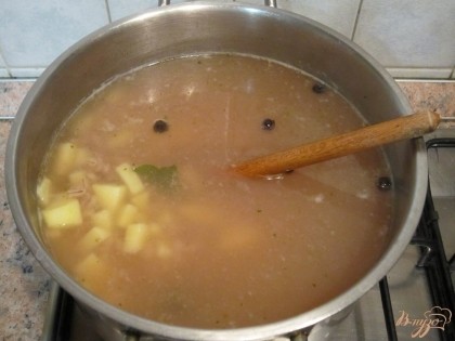 Оставшийся бульон добавить в перловку вместе со специями и варить 25 мин. Картофель нарезать брусочками, выложить в бульон и варить еще 10 мин.