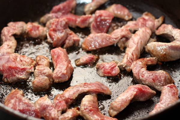Кусочки мяса, нарезанные продолговатыми кусочками поперек волокон, положите неплотно на горячую сковороду.