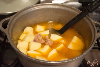 К обжаренному мясу и луку добавляем около 1,5 литра кипятка и подготовленный картофель.
