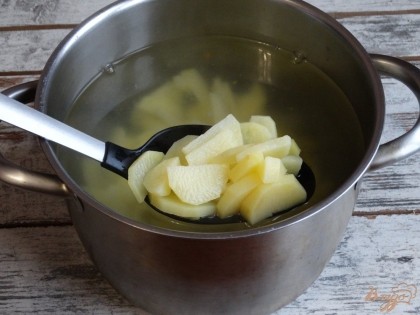 Налейте в кастрюлю воду и поставьте на плиту. Пока вода закипает, очистите и нарежьте картофель. Заложите его в кипяток, варите на медленном огне.