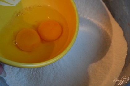 Муку просеять в большую миску, добавить щепотку соли и 2 яйца.