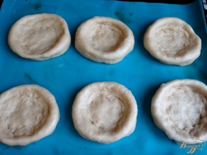 Через указанное время тесто следует слегка обмять, а затем разделить на 6 частей. Из каждого кусочка скатать круглую булочку, после чего сделать заготовки для ватрушек.