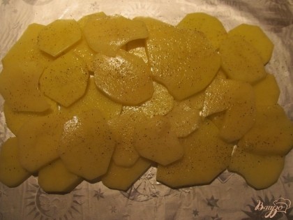 Лист фольги смазываем оливковым маслом, выкладываем слой картофеля, солим и перчим.