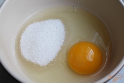 Сахар насыпаем в миску, вбиваем яйцо и взбиваем венчиком.