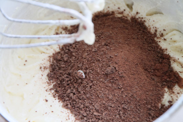 После всех подготовительных этапов можно приступать к замешиванию теста. Мягкое масло разотрите добела с сахарным песком. Затем вбейте яйца и продолжайте взбивать. В конце всыпьте размельчённый шоколад (берите тёмный, с достаточным содержанием какао) и хорошенько перемешайте.