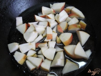 В разогретую сковороду влить две столовые ложки воды и добавить одну столовую ложку сахара. Высыпать кусочки яблок.