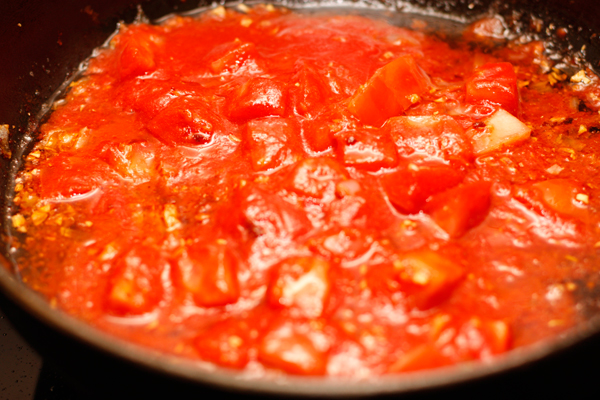 Положите в сковороду мелко нарезанные и очищенные от кожицы томаты вместе с соком.