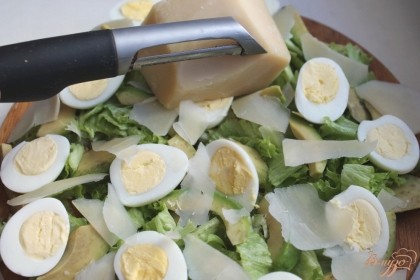 Тонкими лепестками нарезаем твердый выдержанный сыр и кладем на салат.