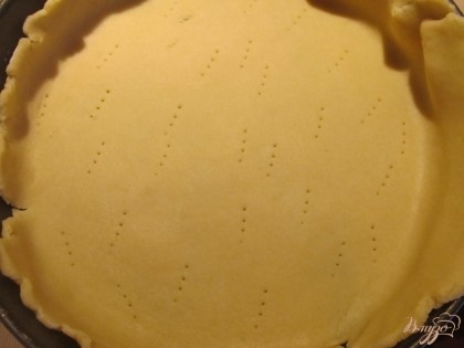 Достаем тесто из холодильника, делим на 2 части и раскатываем такого размера, чтобы можно было сделать бортики. Форму для выпекания смазываем растительным маслом, помещаем раскатанное тесто, прокалываем его вилкой.