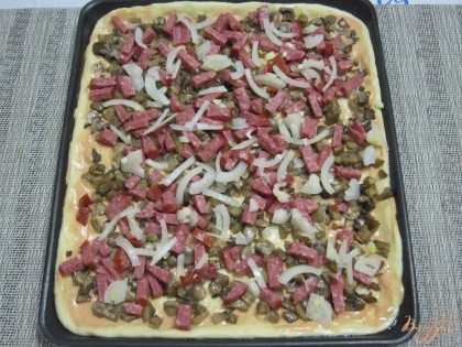 На тесто разложить начинку: грибы, колбасу и лук.