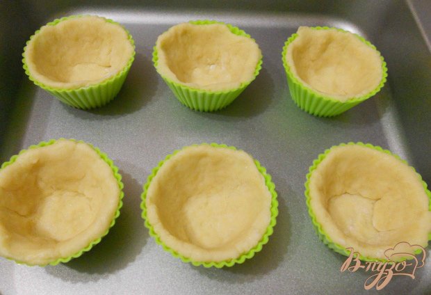 Разделить тесто на 8-10 частей. Каждую - раскатать в лепешку, размером силиконовых или других формочек для кексов. Лепешку поместить в формочку, прижать дно и бока.