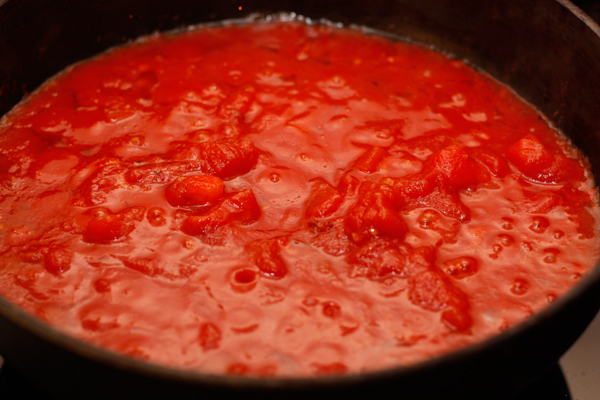 Хорошо измельчите помидоры и добавьте в сковороду к чесноку и перцу, доведите до кипения и дайте покипеть минут 5 на небольшом огне.