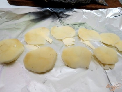 Картофель отвариваем до полуготовности, нарезаем кружочками. Противень застилаем фольгой. На фольгу нарезаем кусочки сливочного масла, на масло выкладываем кружочки картофеля.