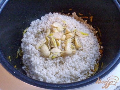 К обжаренным овощам добавляем рис, чеснок, соль, перец черный молотый.