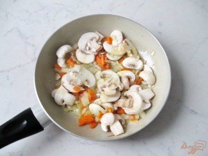 На сковородку с луком и морковкой добавляем нарезанные пластинками шампиньоны и продолжаем тушить до мягкости.