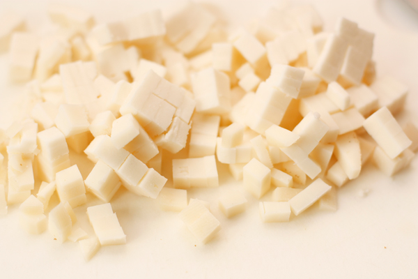 Пока тесто поднимается, нарежьте сыр мелкими кубиками.