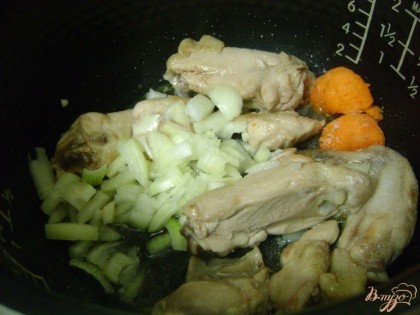 Выкладываем в чашу измельченный лук, а также натертую морковь. Перемешиваем и продолжаем жарить еще 5 минут.