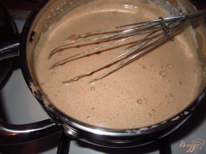 Влейте горячие молоко в шоколадную смесь при этом постоянно мешая венчиком, а потом поставьте на огонь и варите, помешивая до загустения крема.