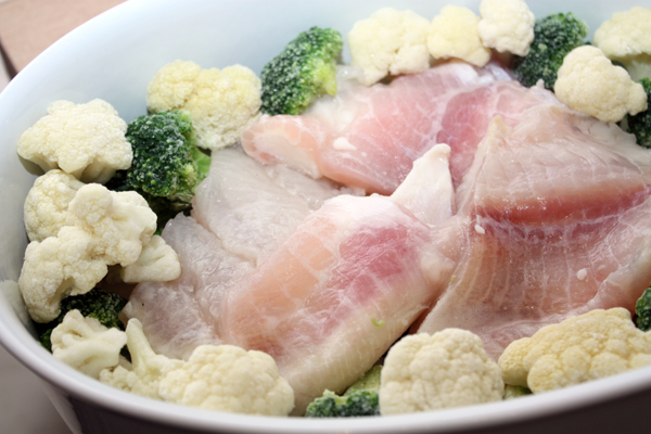 Форму для запекания смажьте маслом, выложите в нее филе рыбы в один-два слоя, чтобы покрыть дно без просветов. Вокруг разложите соцветия капусты.