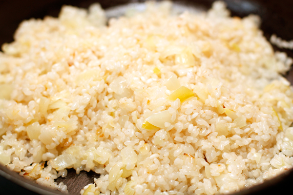 Мелко нарезанный лук спассеруйте на оливковом масле, добавьте рис и готовьте до прозрачности 2-3 минуты.