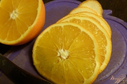 Апельсин вымоем и нарежем тонкими кружками. Чеснок нарежем пластинками.