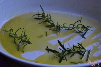 На дно керамической формы налить оливковое масло и уложить веточки розмарина.