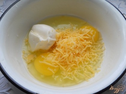 К яйцам добавить натертый сыр и сметану. Посолить немного, поперчить и взбить все вилкой.