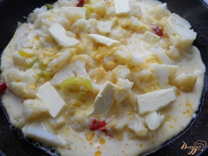 Залить капусту яично-сырной смесью. Сверху распределить кусочки оставшегося сливочного масла. Накрыть сковороду крышкой и готовить на слабом огне минут 5, пока свернутся яйца.