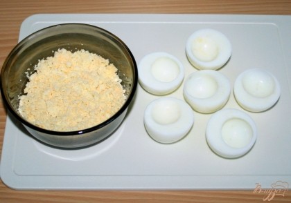 Яйца отварить, очистить разрезать поперек на пополам, отделить желтки от белков. Желтки измельчить вилкой. Дно каждой половинки яиц можно немного подровнять с помощью ножа для устойчивости.