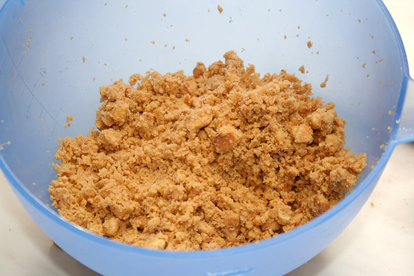 В печенье добавляем мелко порубленное и сильно охлаждённое сливочное масло и тщательно перемешиваем.