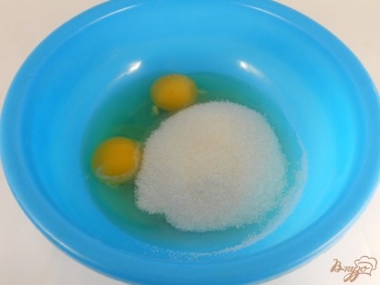 К яйцам добавить щепотку соли и всыпать сахар.