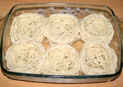 Форму для запекания смазать оливковым маслом, выложить спагетти в виде «гнезд».