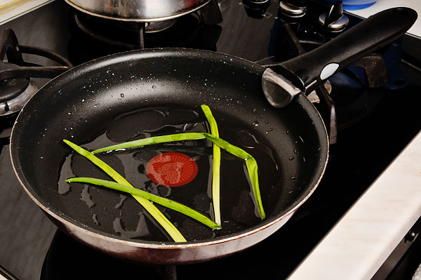 Лук вымыть и высушить, нарезать полосками длинной около 7−10 см. Смазать сковороду маслом (или жиром) положить лук.